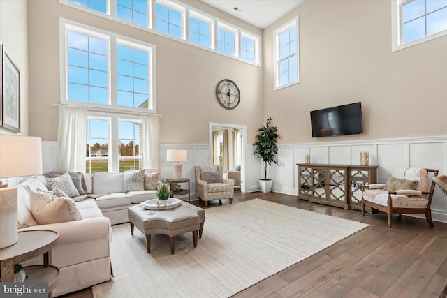 living room with a towering ceiling and wood-type flooring