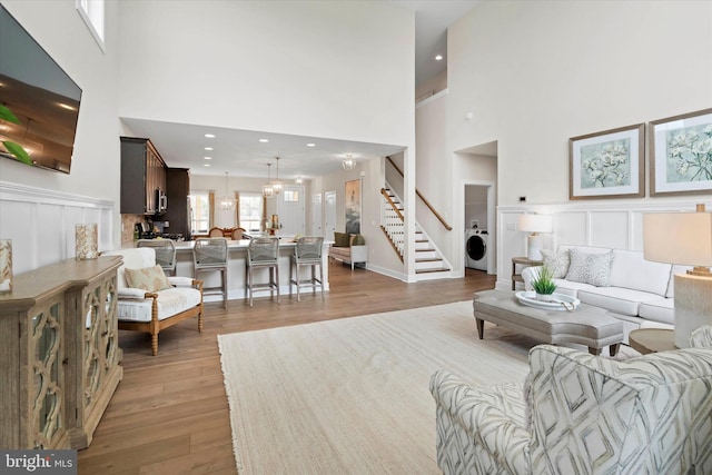 living room featuring washer / clothes dryer, a towering ceiling, and light hardwood / wood-style floors