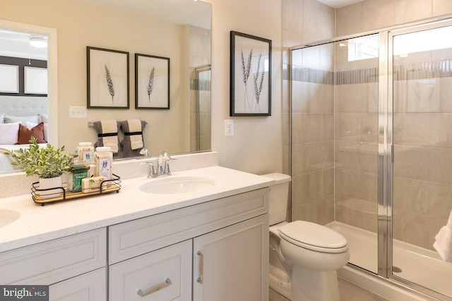 bathroom featuring tile patterned floors, vanity, an enclosed shower, and toilet