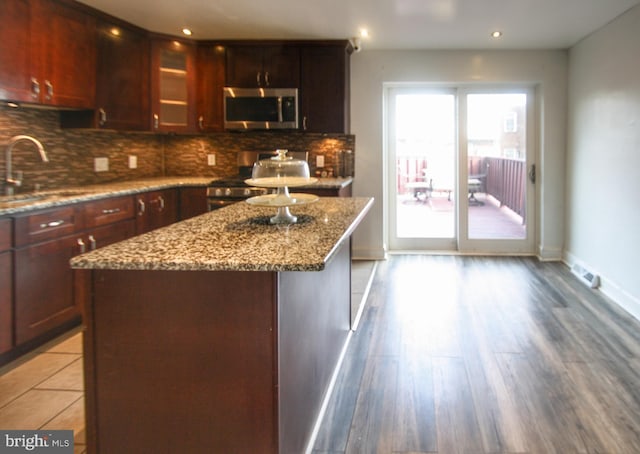 kitchen with sink, a center island, stainless steel appliances, and wood-type flooring