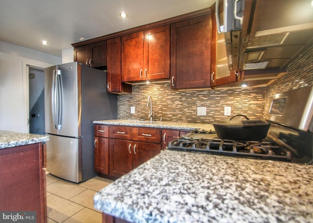 kitchen with light tile patterned flooring, light stone counters, appliances with stainless steel finishes, and tasteful backsplash