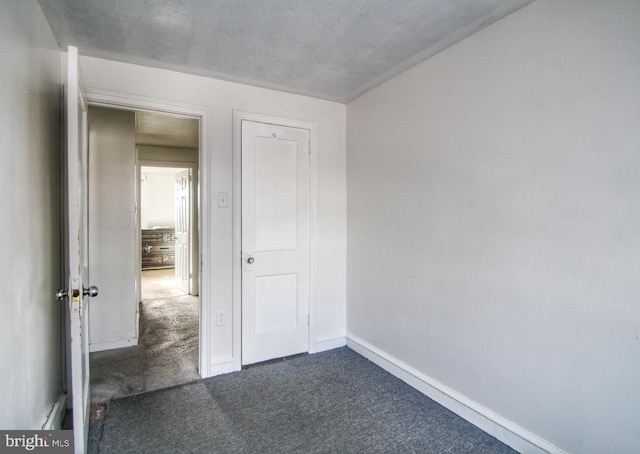 unfurnished bedroom with dark colored carpet and a closet