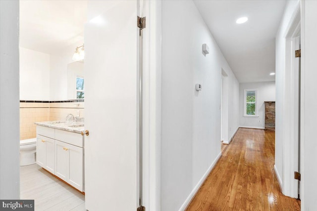 hall with light hardwood / wood-style flooring and tile walls