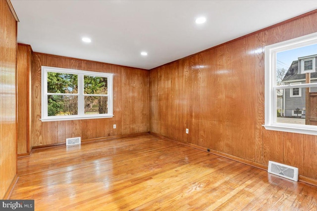 empty room with wooden walls and light hardwood / wood-style floors