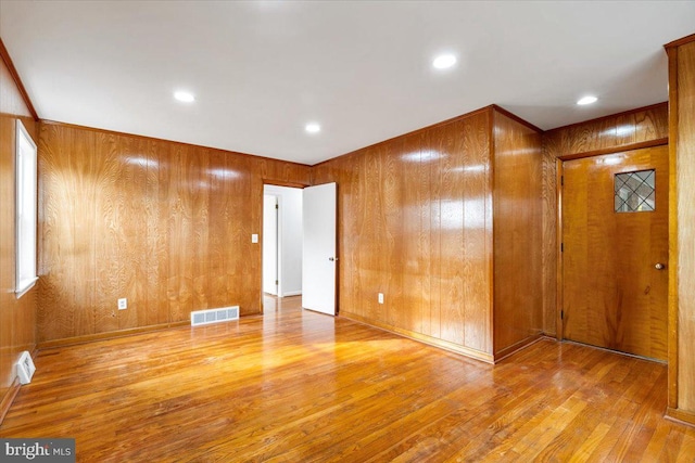 empty room featuring wood walls and light hardwood / wood-style flooring