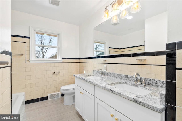 bathroom with vanity, toilet, tile walls, and a bathing tub