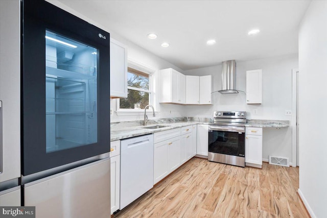 kitchen featuring refrigerator, white cabinets, wall chimney range hood, dishwasher, and stainless steel electric range