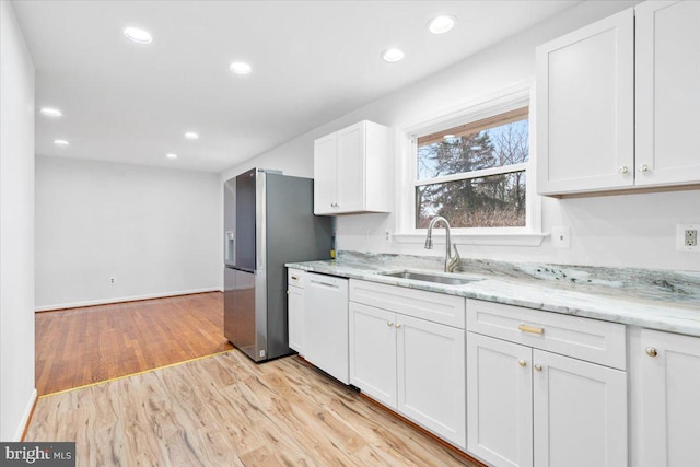 kitchen featuring dishwasher, sink, white cabinets, and light hardwood / wood-style floors