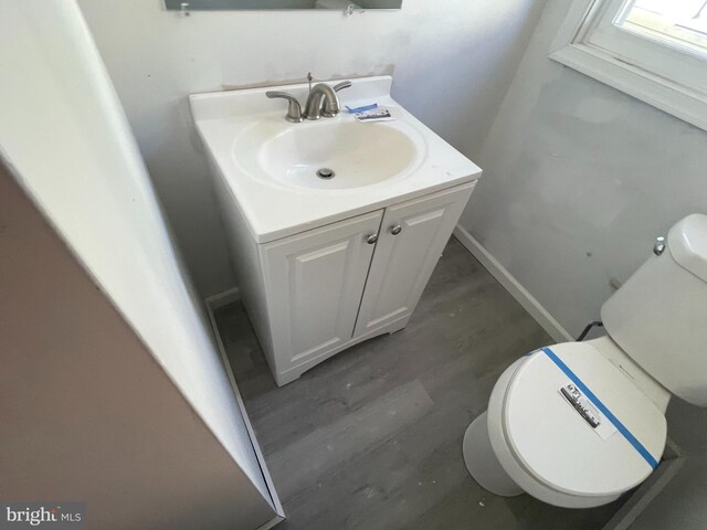 bathroom with wood-type flooring, vanity, and toilet