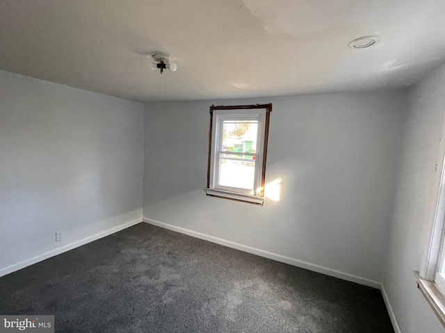 spare room featuring dark carpet