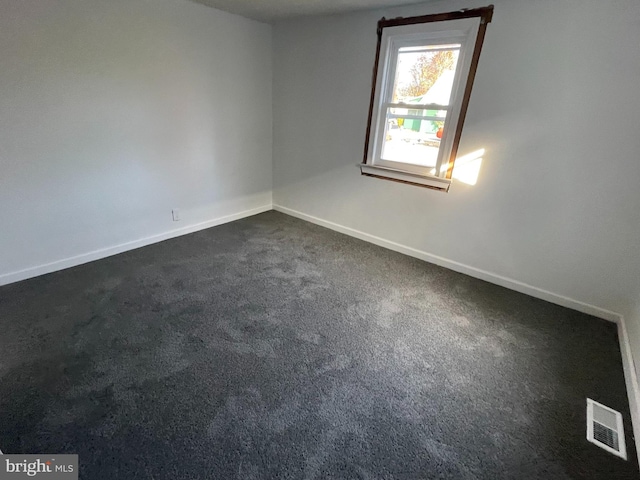 unfurnished room featuring dark colored carpet