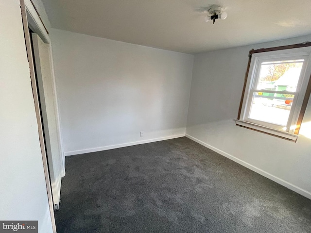 unfurnished room featuring dark colored carpet