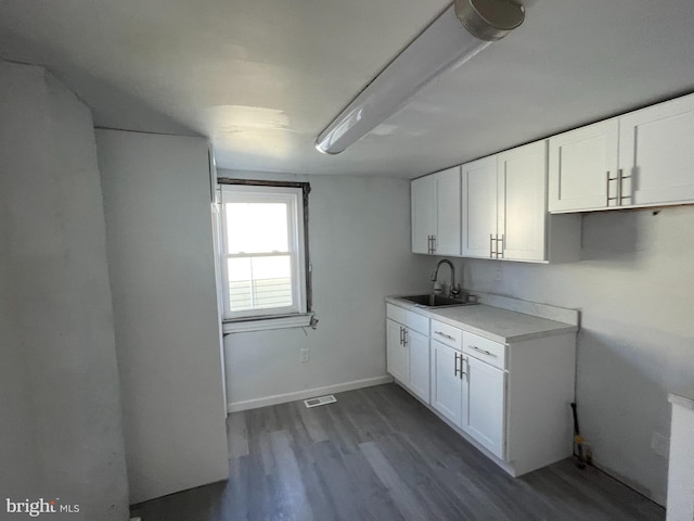 kitchen with radiator heating unit, wood-type flooring, white cabinetry, and sink