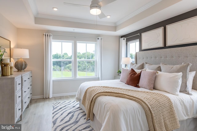 bedroom featuring ceiling fan, light wood-type flooring, ornamental molding, and a tray ceiling