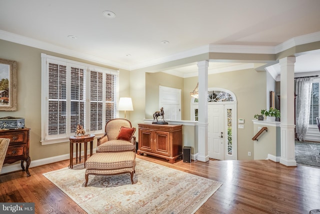 living area featuring decorative columns, crown molding, plenty of natural light, and wood-type flooring