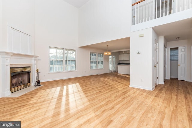 unfurnished living room with a high ceiling and light wood-type flooring