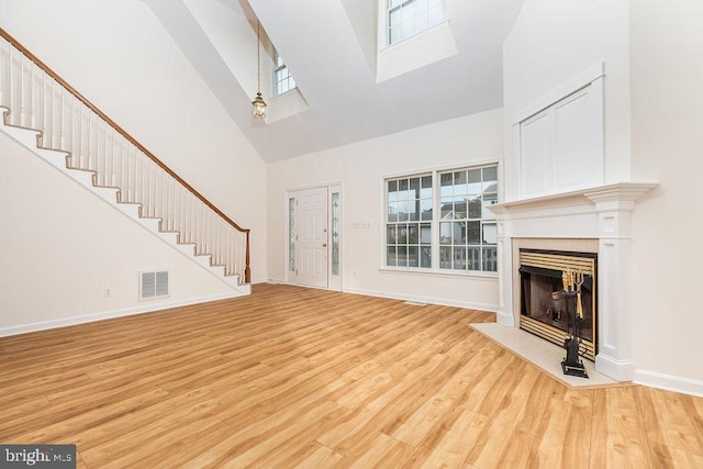 unfurnished living room featuring high vaulted ceiling and light hardwood / wood-style floors