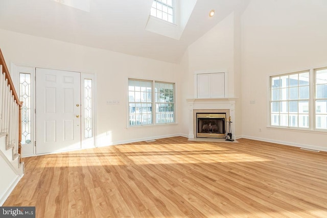 unfurnished living room featuring high vaulted ceiling and light hardwood / wood-style flooring