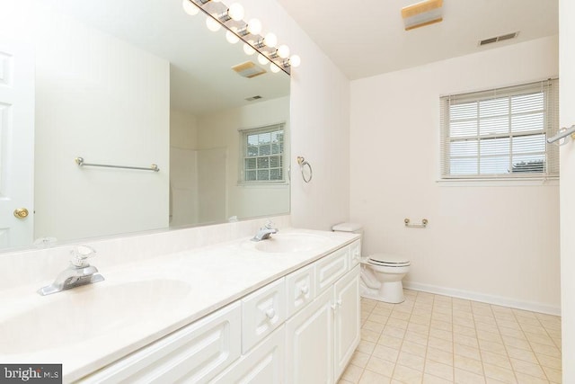 bathroom with tile patterned floors, vanity, a healthy amount of sunlight, and toilet