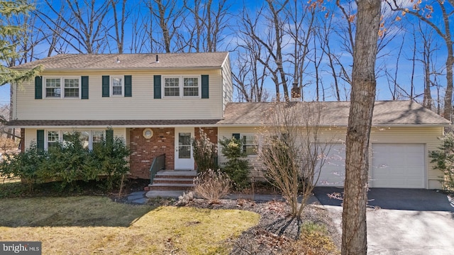 view of front of house featuring aphalt driveway, a front yard, and a garage