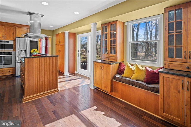 kitchen with dark countertops, island exhaust hood, ornate columns, and a kitchen island