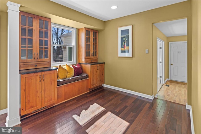 hall featuring ornate columns, recessed lighting, dark wood-type flooring, and baseboards