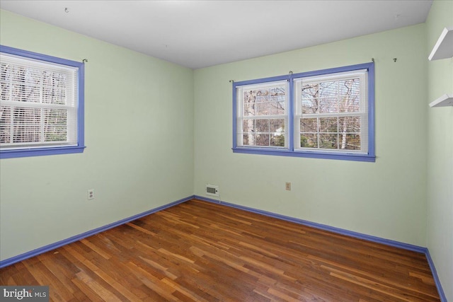 unfurnished room with visible vents, baseboards, and wood finished floors