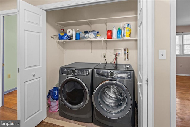 laundry area featuring baseboards, wood finished floors, washing machine and dryer, and laundry area