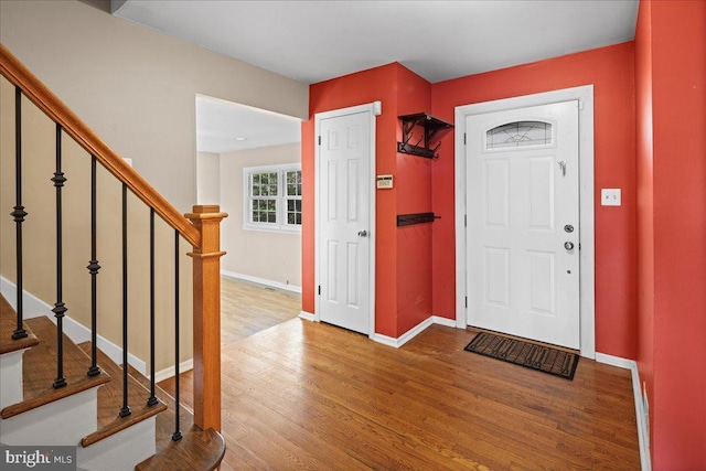 entrance foyer with stairway, baseboards, and wood finished floors