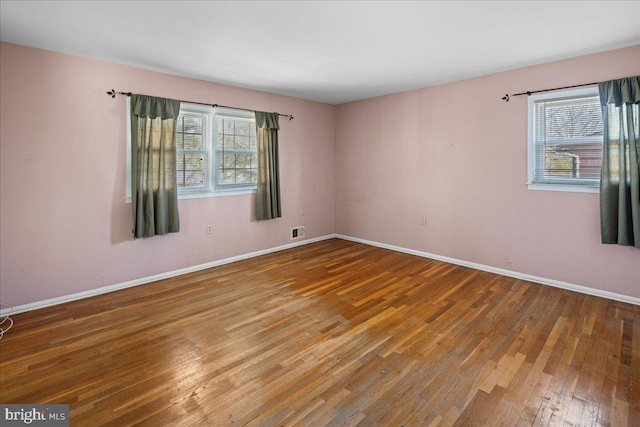 spare room featuring visible vents, baseboards, and hardwood / wood-style floors