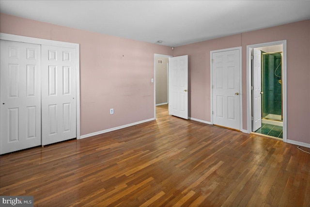 unfurnished bedroom featuring wood finished floors, baseboards, a closet, and connected bathroom