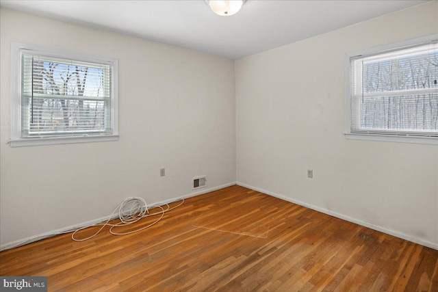 unfurnished room with visible vents, baseboards, and wood finished floors