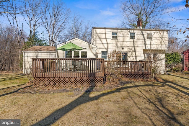 rear view of property with a yard, a deck, and a chimney