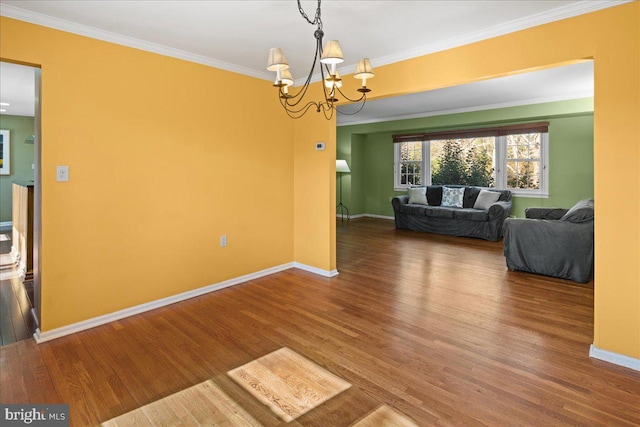 interior space featuring baseboards, an inviting chandelier, wood finished floors, and crown molding