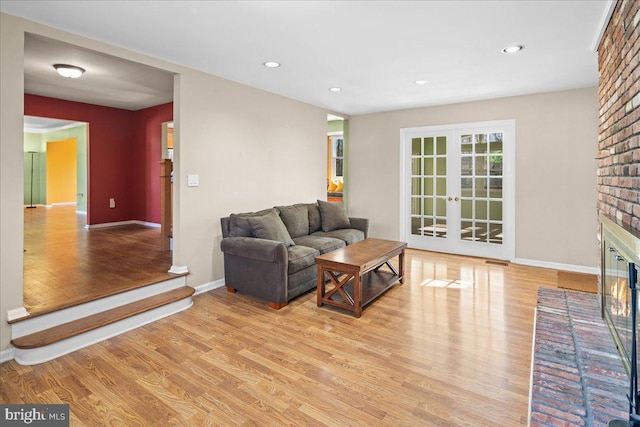 living area featuring wood finished floors, visible vents, baseboards, a fireplace, and french doors