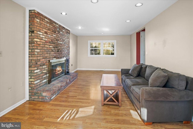 living room featuring recessed lighting, a brick fireplace, baseboards, and wood finished floors