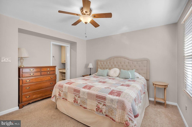 carpeted bedroom with multiple windows, ensuite bathroom, and ceiling fan