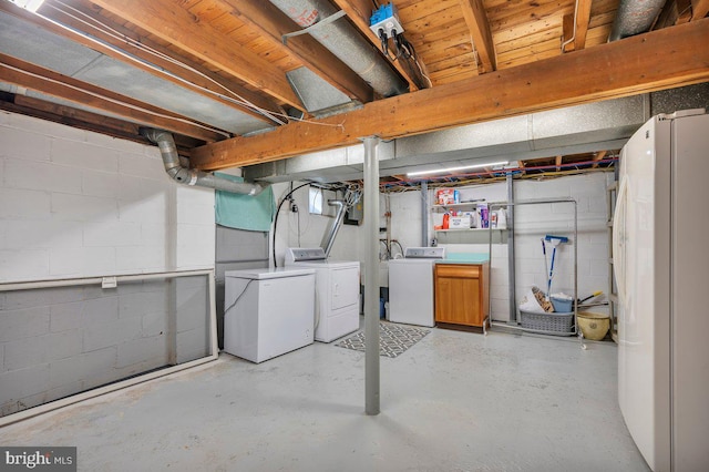 basement featuring refrigerator, white fridge, and washer and clothes dryer