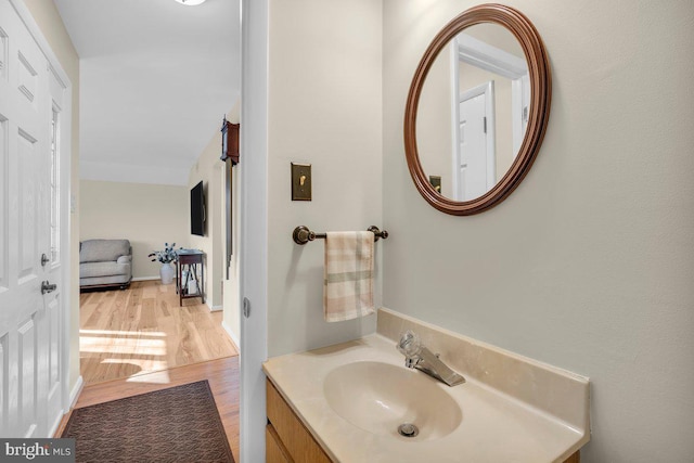 bathroom with hardwood / wood-style flooring, vanity, and lofted ceiling