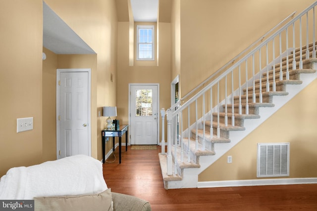 foyer entrance with a towering ceiling and dark hardwood / wood-style floors