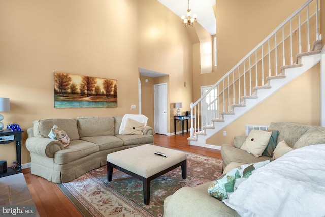 living room with a chandelier, a high ceiling, and hardwood / wood-style flooring