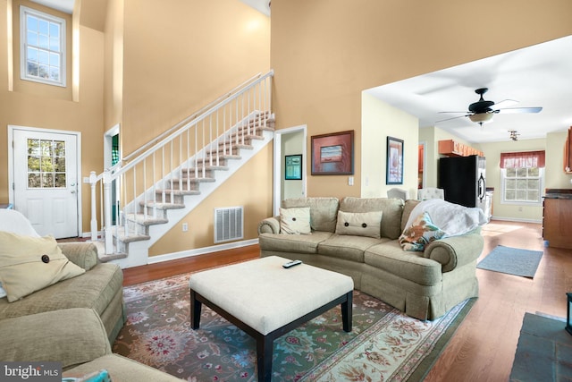 living room featuring hardwood / wood-style flooring, ceiling fan, a healthy amount of sunlight, and a high ceiling