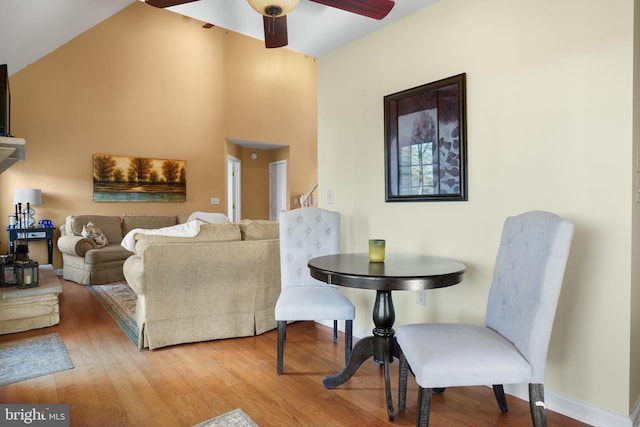 living room with hardwood / wood-style flooring, ceiling fan, and vaulted ceiling