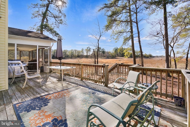 wooden deck with a sunroom and a rural view