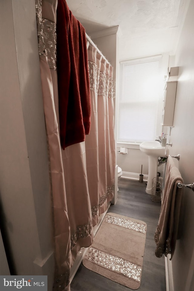 bathroom with a shower with curtain, wood-type flooring, toilet, and ornamental molding