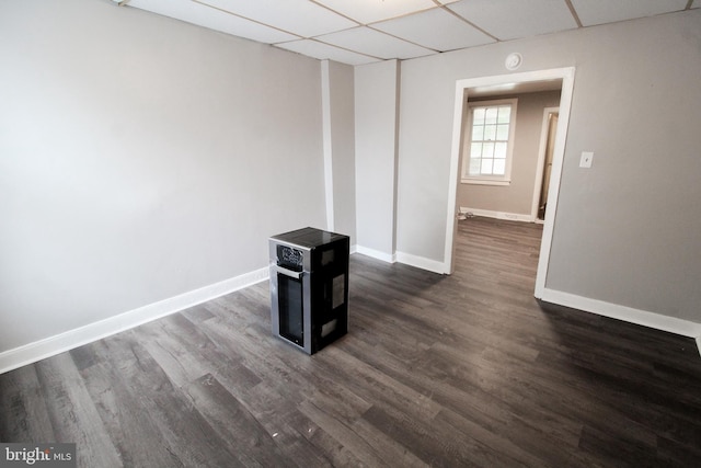 unfurnished room with a drop ceiling and dark wood-type flooring