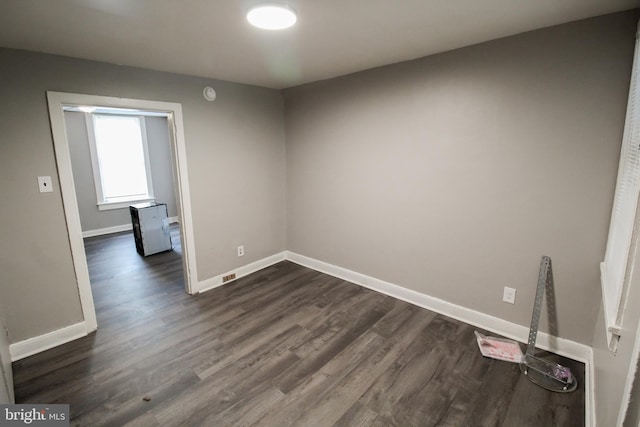 unfurnished room with dark wood-type flooring