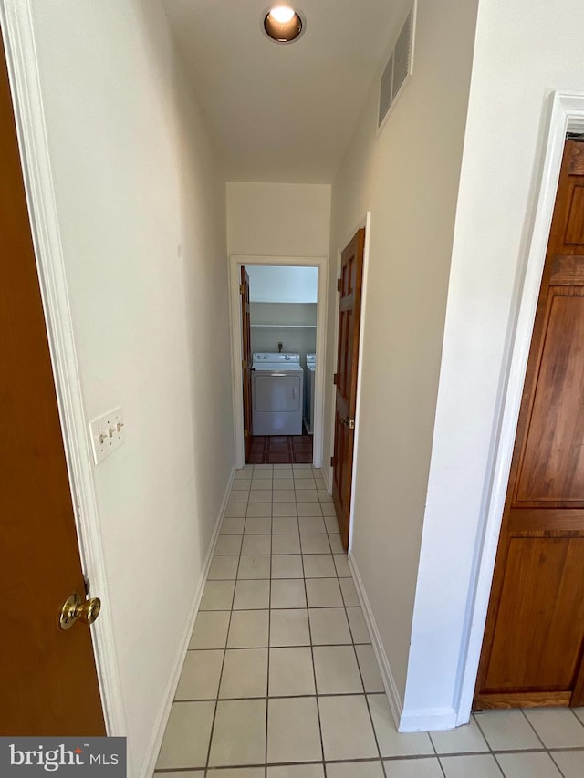 corridor with light tile patterned floors and washer and dryer