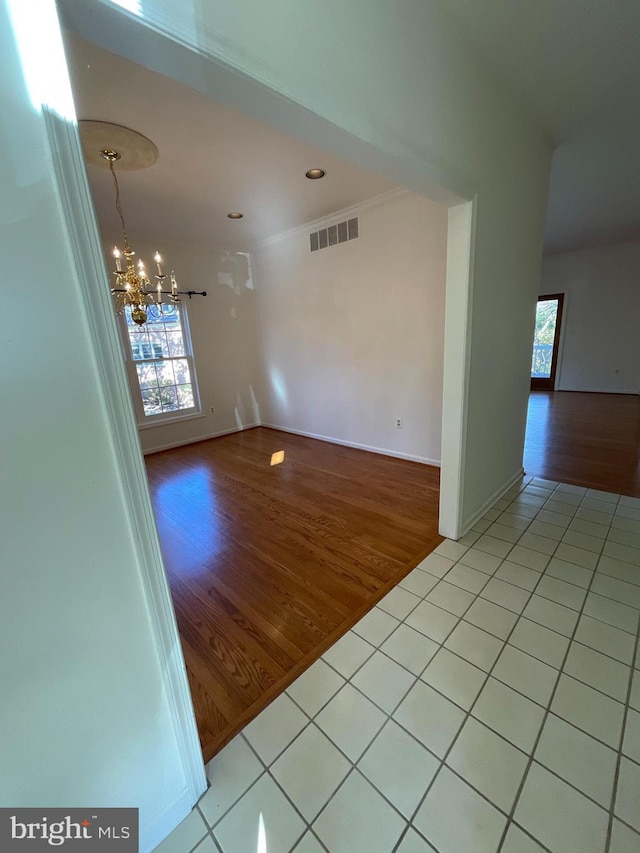 spare room with light hardwood / wood-style floors and an inviting chandelier