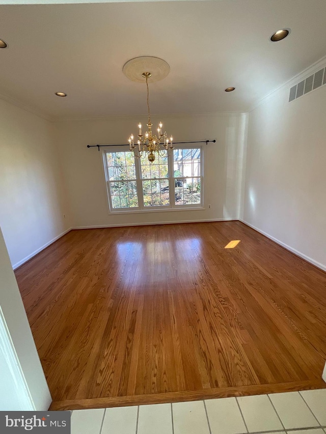 unfurnished dining area with crown molding, a notable chandelier, and hardwood / wood-style flooring